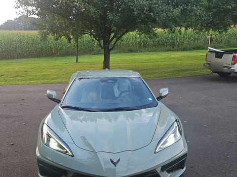 Front of a grey-green Chevrolet Corvette after an exterior detail, headlights on at dusk
